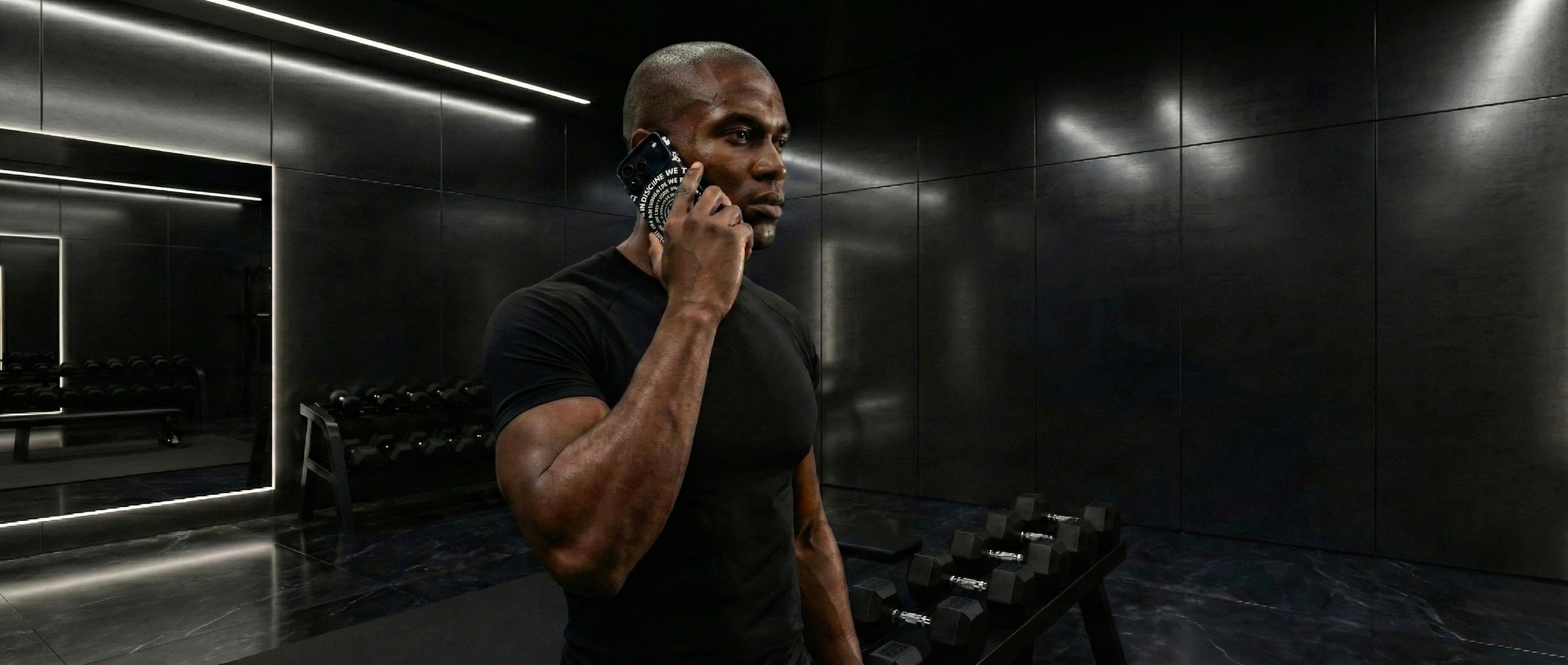 A man in the gym, holding a phone to his ear with an Aesmor case